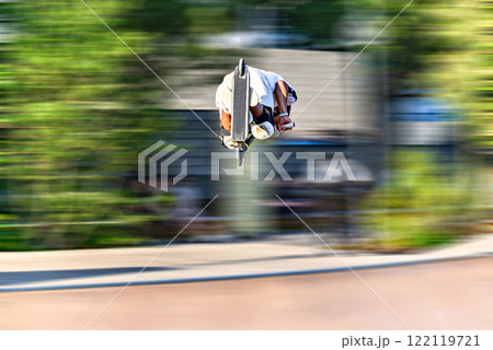 Young man practicing Scootering (Freestyle Scootering) in the new SkatePark in the central park of Igualada, Barcelona, Spain. blurred background 122119721
