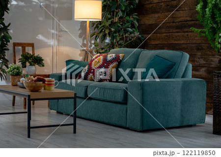 A Cozy Living Room Featuring a Stylish Sofa Surrounded by Beautiful Greenery and Decor A Cozy Living Room Featuring a Stylish Sofa Surrounded by Beautiful Greenery and Decor 122119850