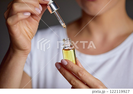Skincare. Close up beauty portrait of a beautiful woman with glowing skin is applying a vitamin C skincare product with a pipette dropper. Serum. Moisturizing and nourishing Skincare. Close up beauty portrait of a beautiful woman with glowing skin is applying a vitamin C skincare product with a pipette dropper. Serum. Moisturizing and nourishing 122119927