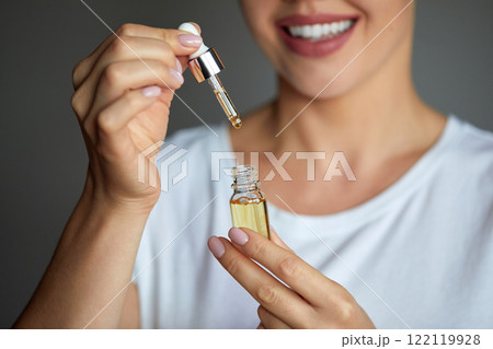 Skincare. Close up beauty portrait of a beautiful woman with glowing skin is applying a vitamin C skincare product with a pipette dropper. Serum. Moisturizing and nourishing Skincare. Close up beauty portrait of a beautiful woman with glowing skin is applying a vitamin C skincare product with a pipette dropper. Serum. Moisturizing and nourishing 122119928