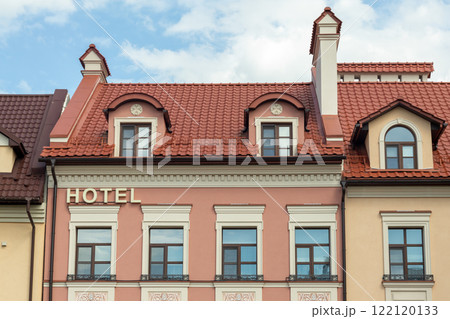 Charming hotel building facade with decorative windows and red tiled roof Charming hotel building facade with decorative windows and red tiled roof 122120133