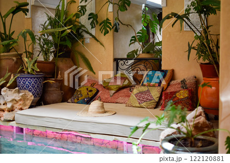 Balinese Bed with colorful cushions, decorative plants, a hat and swimming pool 122120881