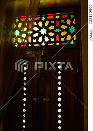 Window with Arabic colored lattice, soft curtain dropped on side and dim light Window with Arabic colored lattice, soft curtain dropped on side and dim light 122120900