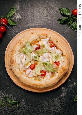 Fresh salad pizza with turkey, lettuce, cherry tomatoes, and egg slices on a wooden board 122122549