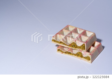 Trend white Dubai chocolate with pistachio, dried raspberry, tahini and kadaif, on white background with copy space, isolated, showing the filling. Confectionery and handmade sweets, chocolatier 122123084