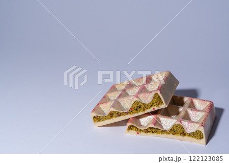 Trendy white Dubai chocolate with pistachio, dried raspberry, tahini and kadaif, on white background with copy space, isolated, showing the filling. Confectionery and handmade sweets, chocolatier Trendy white Dubai chocolate with pistachio, dried raspberry, tahini and kadaif, on white background with copy space, isolated, showing the filling. Confectionery and handmade sweets, chocolatier 122123085