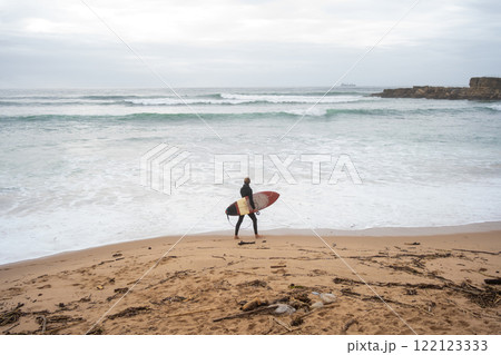 Mid distance of anonymous surfer walking on Mid distance of anonymous surfer walking on 122123333