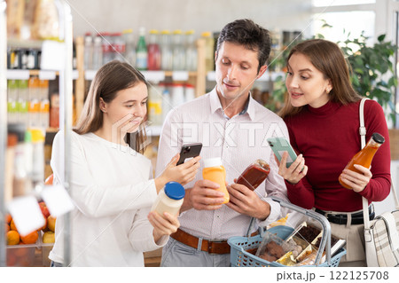 Family with teenage girl scanning QR on bottles of sauce in supermarket 122125708