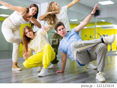 Teenage girls and a boy performing breakdance poses in dance hall Teenage girls and a boy performing breakdance poses in dance hall 122125819
