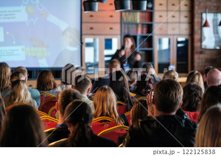 Audience attending a business presentation in a modern conference room setup Audience attending a business presentation in a modern conference room setup 122125838