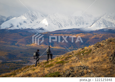 Hikers exploring a scenic autumn mountain landscape with snow covered peaks 122125848