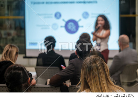 Audience attentively listening to female speaker during business presentation 122125876