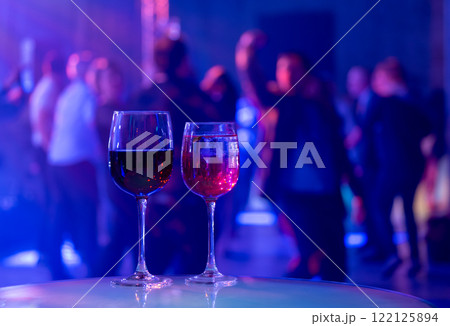 Glasses of wine at a lively party with vibrant lights 122125894
