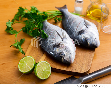 Two doradas on cutting board with herbs oil and lime Two doradas on cutting board with herbs oil and lime 122126062