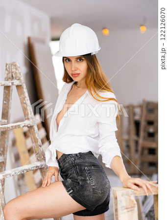 Seductive young woman poses in a hardhat and in a revealing outfit 122126070