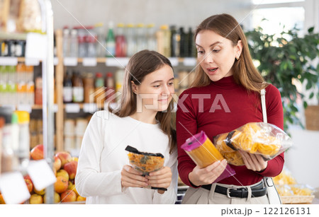 Teenage girl and her mother choosing pasta in grocery store 122126131