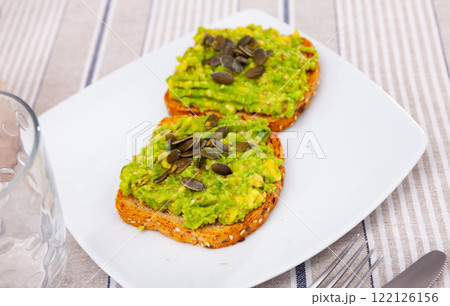 Sandwich with guacamole butter and seeds on whole grain bread, healthy eating concept Sandwich with guacamole butter and seeds on whole grain bread, healthy eating concept 122126156