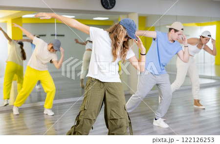 Teenage girl in sunglasses and cap training breakdance Toprock moves in dance hall Teenage girl in sunglasses and cap training breakdance Toprock moves in dance hall 122126253