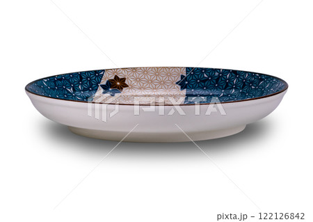 Side view of empty blue and brown star pattern dark edge ceramic plate isolated on white background. 122126842
