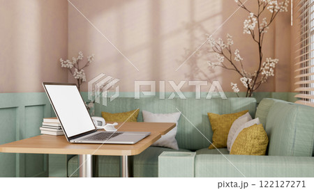 A laptop placed on a wooden table in modern pastel cafe or office lounge. 122127271