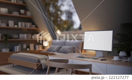 A computer desk in a cozy, contemporary bedroom features a computer with a white screen mockup. 122127277