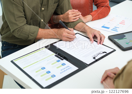 Asian couple reviewing and sign contract financial documents with the guidance of  advisor at home,collaboration and thoughtful planning for financial success 122127696