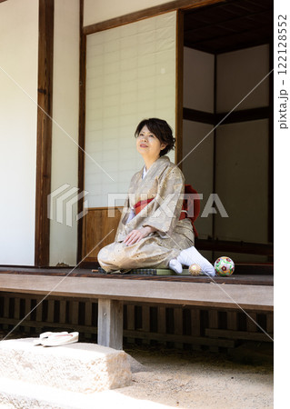 縁側で少し正座を崩して座っている女性 122128552