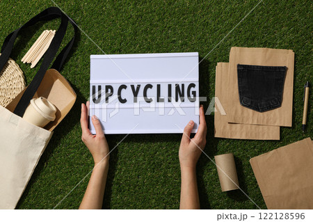 Light box with text in hands, bag and materials for upcycling on green background, top view Light box with text in hands, bag and materials for upcycling on green background, top view 122128596