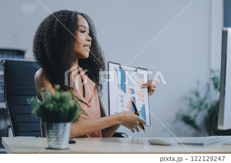 Female business person using digital tablet and laptop or remote working at home office, looking at digital tablet watching webinar, learning training, studying online seminar or video calling. 122129247