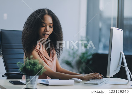 Female business person using digital tablet and laptop or remote working at home office, looking at digital tablet watching webinar, learning training, studying online seminar or video calling. 122129249