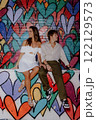 A couple poses by a colorful heart mural in the city, happily enjoying each other 122129573