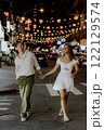 Charming couple strolling under festive city lights, fully embracing their special moment 122129574