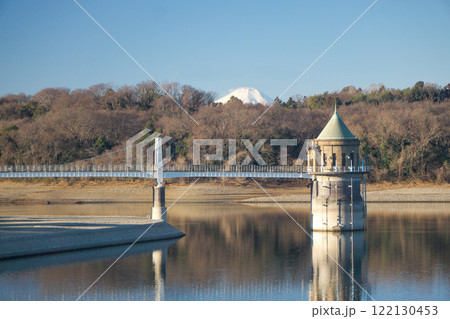 青空の冬の狭山湖堰堤から見る取水塔と山頂のみ見える富士山 122130453