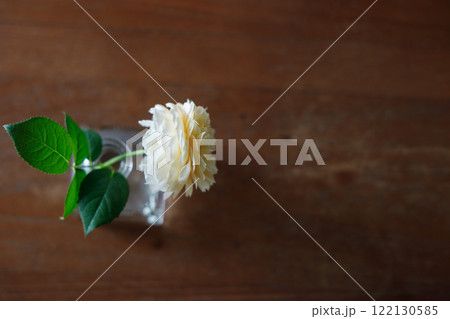 Closeup of Yellow beautiful blooming rose in glass vase on wooden table. Closeup of Yellow beautiful blooming rose in glass vase on wooden table. 122130585