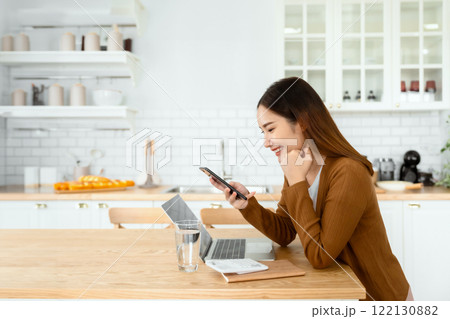 Happy young asian woman relax in domestic kitchen at home 122130882