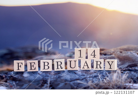 February 14 is the date of the Valentine's Day holiday made of wooden cubes on the background of blue mountains at sunset or sunrise. Valentines Day Celebration takes place on the widely recognized February 14 is the date of the Valentine's Day holiday made of wooden cubes on the background of blue mountains at sunset or sunrise. Valentines Day Celebration takes place on the widely recognized 122131107