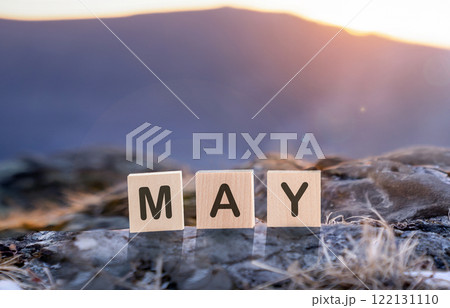 May is the word for the month, made of wooden cubes against the background of blue mountains, during sunrise or sunset. The beautiful and vibrant month of May, full of natural landscapes and serene May is the word for the month, made of wooden cubes against the background of blue mountains, during sunrise or sunset. The beautiful and vibrant month of May, full of natural landscapes and serene 122131110