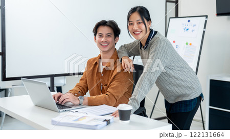 A portrait of two positive Asian businesspeople, a male and female, both smiling at the camera. 122131664