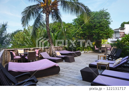 Relaxation area with sun beds and a coconut palm tree in a tropical resort 122131717