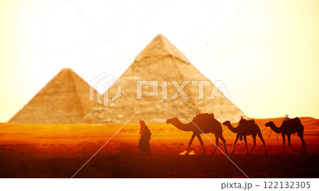 Horizontal banner with caravan of camels and Great Pyramids of Chephren and Cheops, Cairo, Egypt. Man with three dromedary in two pyramids, Giza complex (Giza Necropolis). On sunrise sky background 122132305