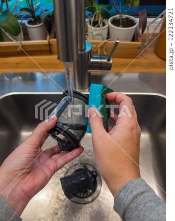 Hands cleaning a dishwasher machine filter under running water in kitchen sink. High quality photo 122134721