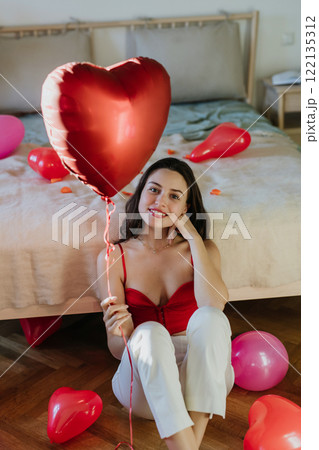 Beautiful woman holding heart shaped balloon in hand. Concept of Valentine's Day, love and romance. 122135312