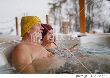 Senior couple bathing in hot tub during cold winter day. Romantic wellness getaway with spa during Valentine's weekend. Senior couple bathing in hot tub during cold winter day. Romantic wellness getaway with spa during Valentine's weekend. 122135462