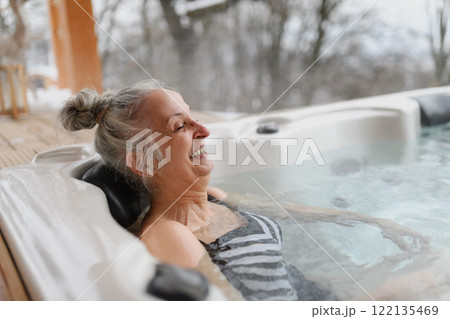 Senior woman bathing in hot tub during cold winter day, enjoying peaceful moment. Senior woman bathing in hot tub during cold winter day, enjoying peaceful moment. 122135469