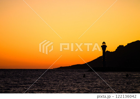 Dark orange red sunset with lighthouse and mountains in Cannes, France Dark orange red sunset with lighthouse and mountains in Cannes, France 122136042