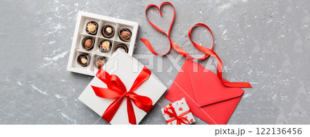 Envelope on colored background for Valentine Day with gift box and chocolate. Heart shaped with gift box of chocolates top view with copy space Envelope on colored background for Valentine Day with gift box and chocolate. Heart shaped with gift box of chocolates top view with copy space 122136456