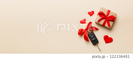 Black car key in a present box with a ribbon and red heart on colored background. Valentine day composition Top view Black car key in a present box with a ribbon and red heart on colored background. Valentine day composition Top view 122136481