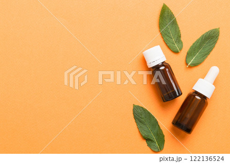 Natural Mint Essential Oil in a Glass Bottle. organic cosmetics with herbal extracts of mint on colored background Natural Mint Essential Oil in a Glass Bottle. organic cosmetics with herbal extracts of mint on colored background 122136524