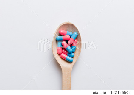 Vitamin capsules in a spoon on a colored background. Pills served as a healthy meal. Red soft gel vitamin supplement capsules on spoon Vitamin capsules in a spoon on a colored background. Pills served as a healthy meal. Red soft gel vitamin supplement capsules on spoon 122136603