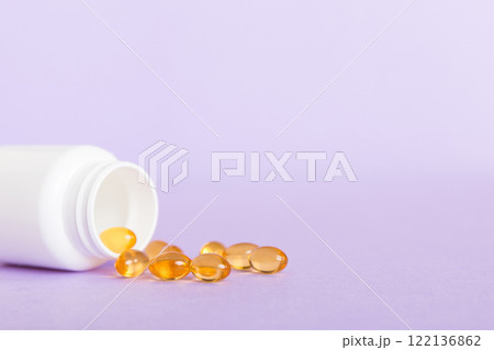 Soft gels pills with Omega-3 oil spilling out of pill bottle close-up. Gel capsules bottle white surface. Omega 3, multivitamins, Calcium, antibiotics. Health. Immunity Soft gels pills with Omega-3 oil spilling out of pill bottle close-up. Gel capsules bottle white surface. Omega 3, multivitamins, Calcium, antibiotics. Health. Immunity 122136862